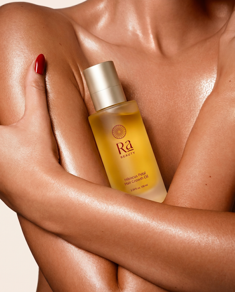 Ra Beauty Hibiscus Petal Hair Growth Oil held against glowing skin